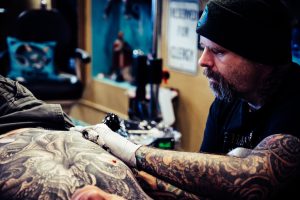 Tattoo artist skillfully inks intricate design on clients back in a tattoo studio.